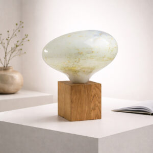 Sculptural hand-blown glass lamp with organic form and subtle green-gold texture, presented in a refined gallery-style interior.